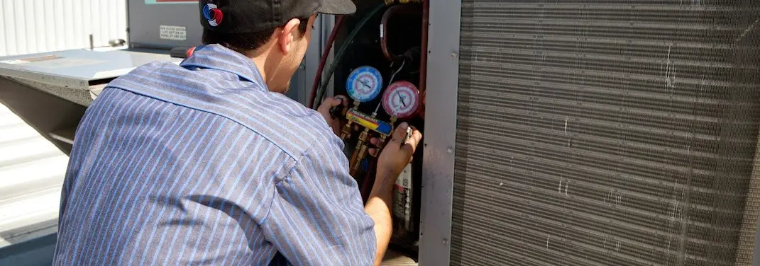 HVAC technician servicing a condenser unit in Etowah